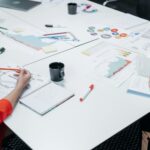 Team discussing data and charts in an office setting with coffee and notes.